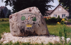 Blick auf einen Findling auf den das Wappen von Grünewalde gemalt ist.
