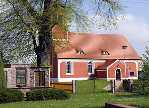 Blick zur Rückersdorfer Kirche. Im Vordergrund steht eine Gedenktafel.