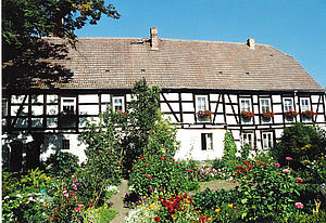 Blick auf die Rückseite der Wahrenbrücker Mühle mit Fachwerk. Im Vorgrund ein blühender Garten.